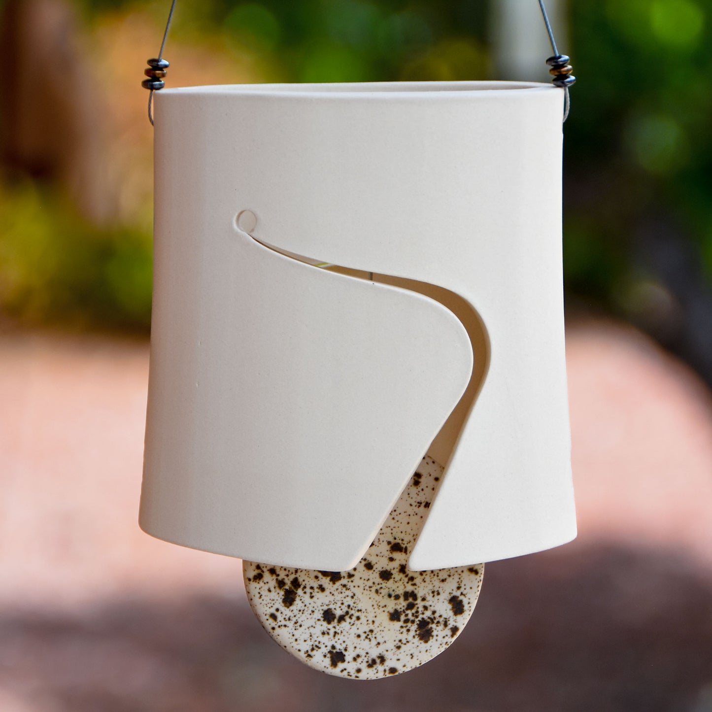 Sculptural white ceramic wind chime with contemporary sound hole cut and speckled black and white bell striker