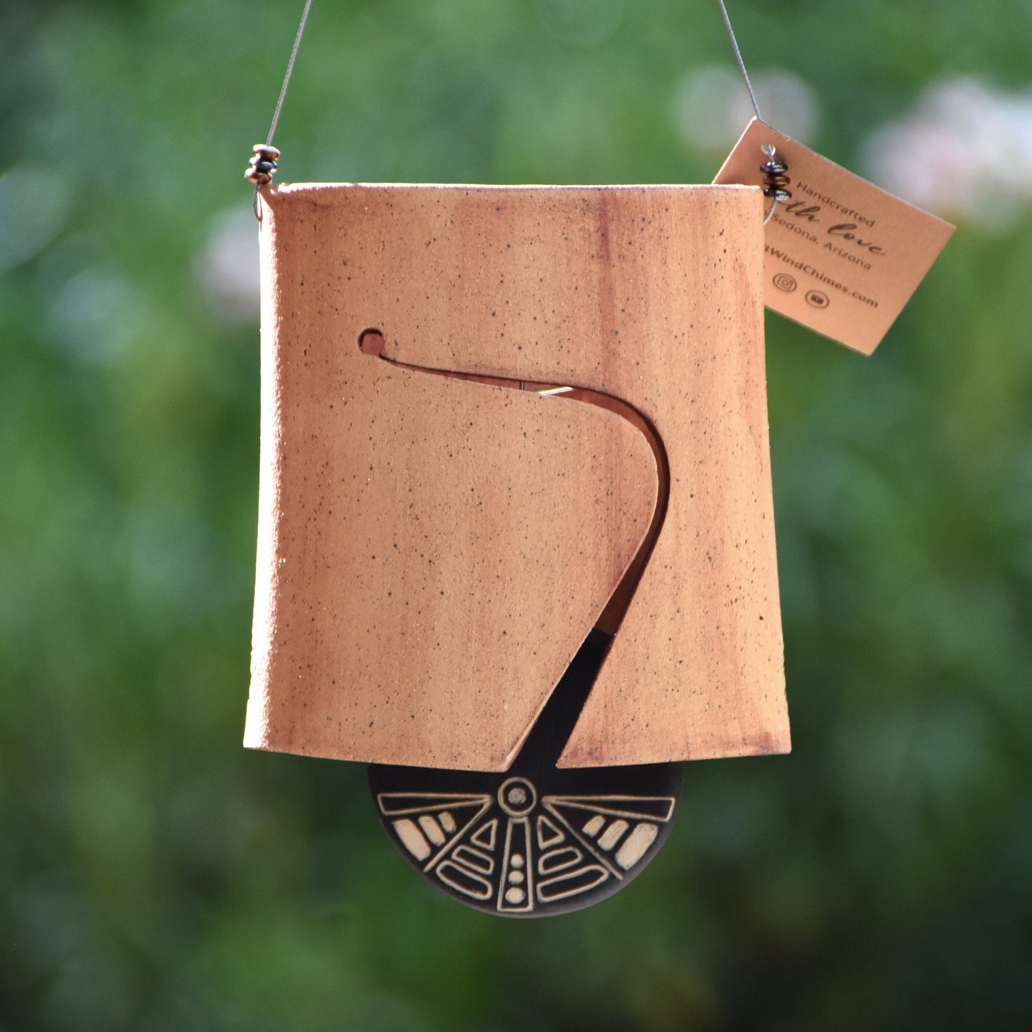 Modern, speckled buff ceramic wind chime bell that was stained with red iron oxide. The bell features a black and white sgraffito wind clapper carved with an abstract motif