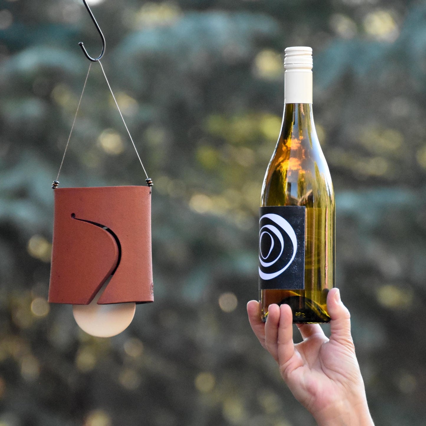 Image showing Hawaiian red wind chime bell with white clapper and wine bottle next to it for size comparison