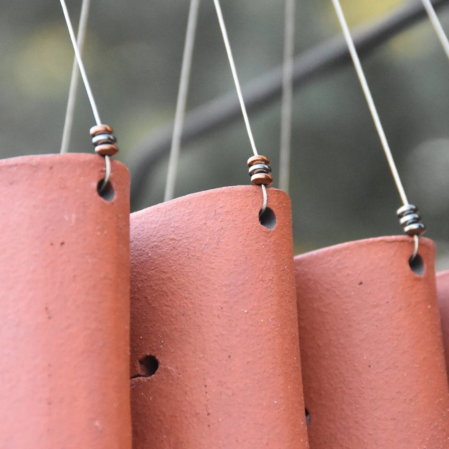Closeup of rustic red wind chimes showcasing steel beads attached tot he wire they are hanging from