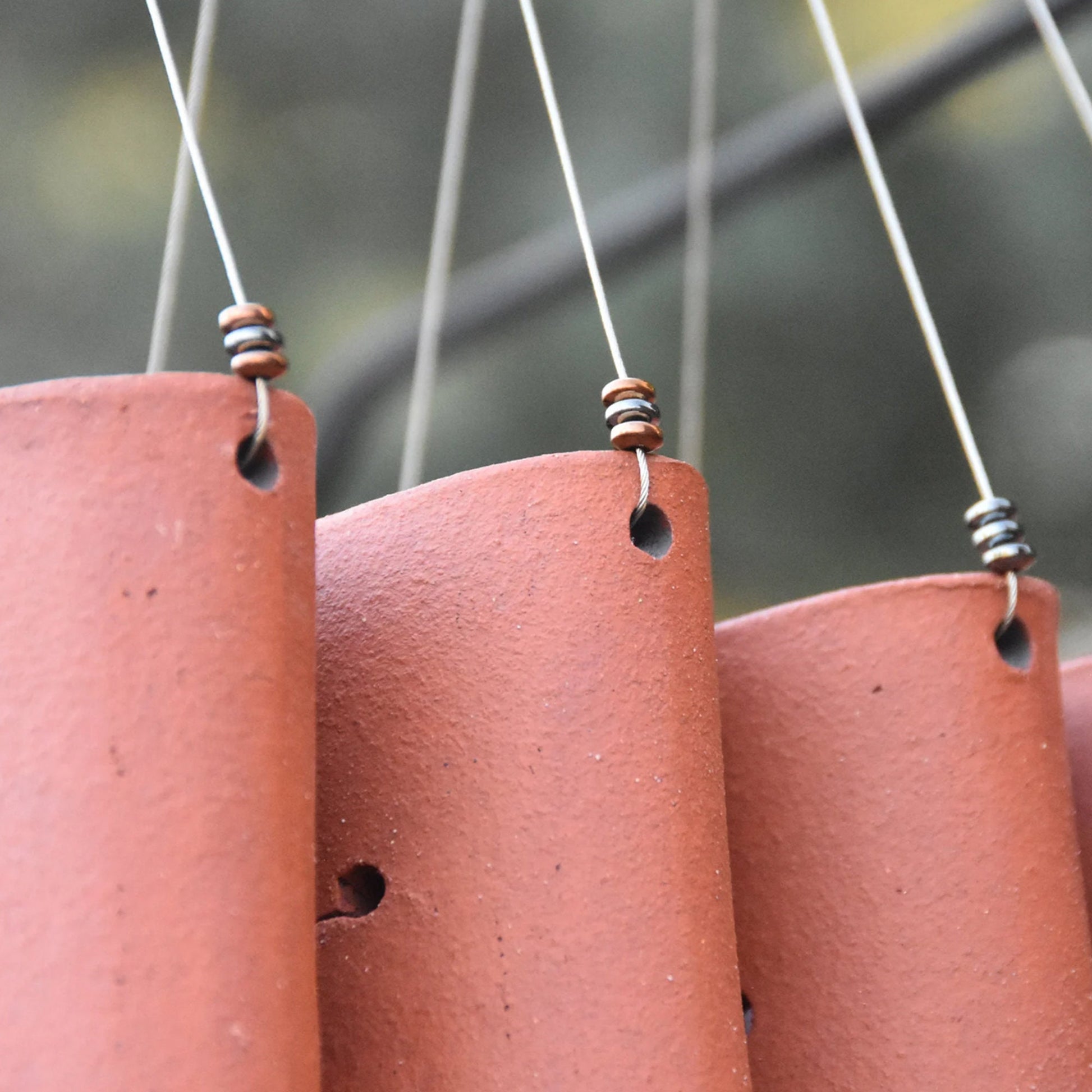Closeup of rustic red wind chimes showcasing steel beads attached tot he wire they are hanging from
