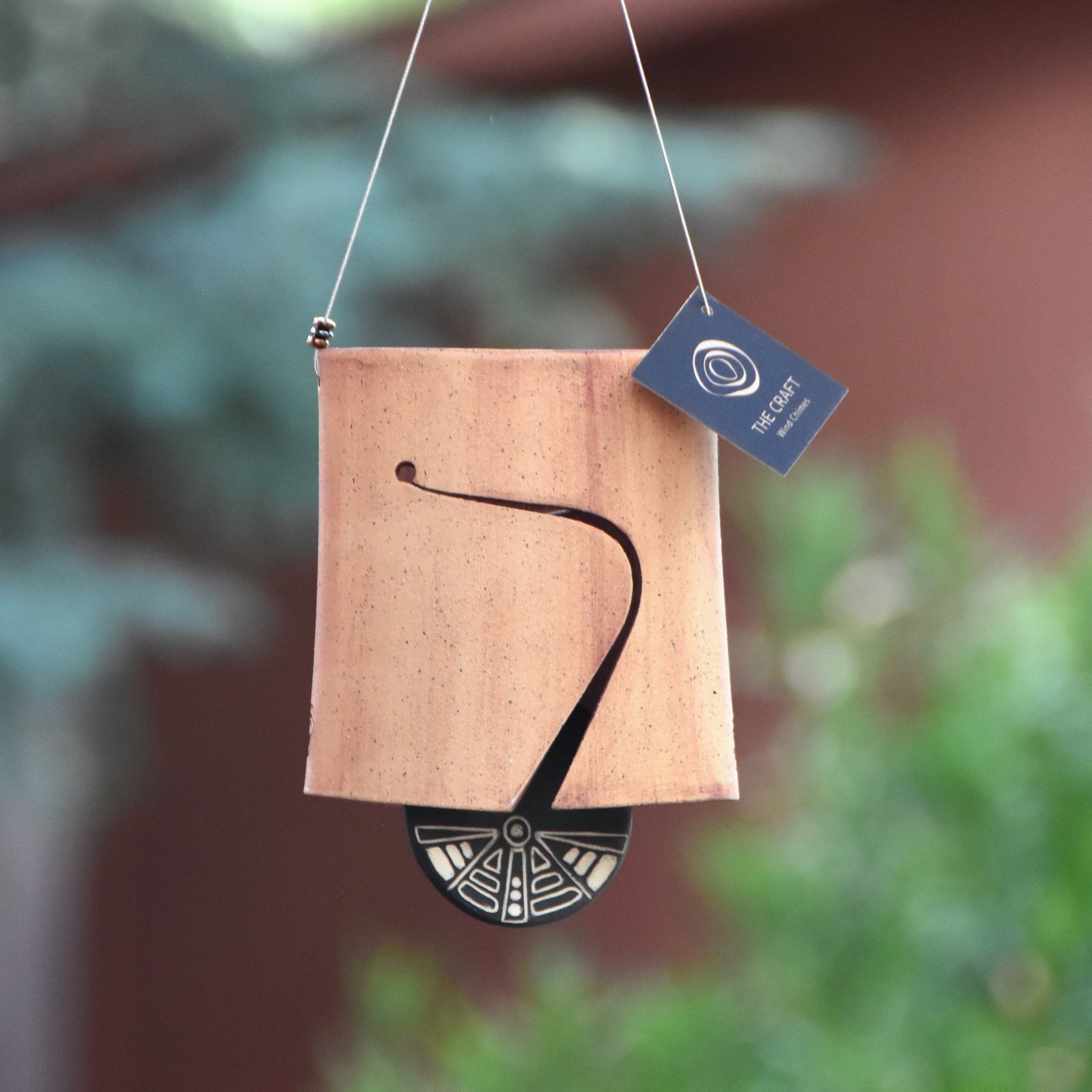 Modern, speckled buff ceramic wind chime bell that was stained with red iron oxide. The bell features a black and white sgraffito wind clapper carved with an abstract motif