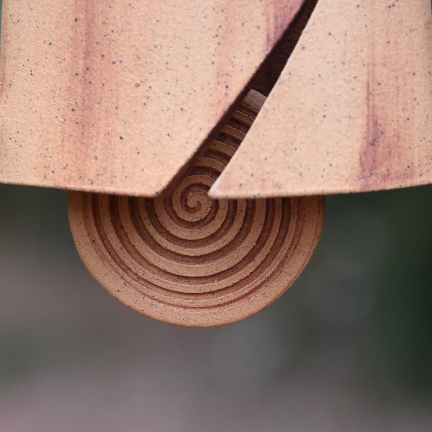 Closeup view of round spiral carved wind clapper which was stained with red iron oxide.