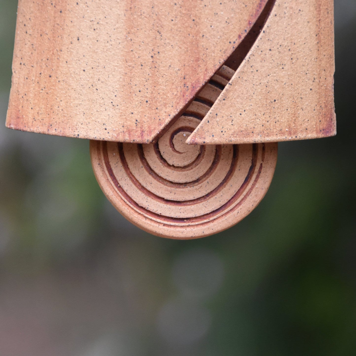 Closeup view of round spiral carved wind clapper which was stained with red iron oxide.