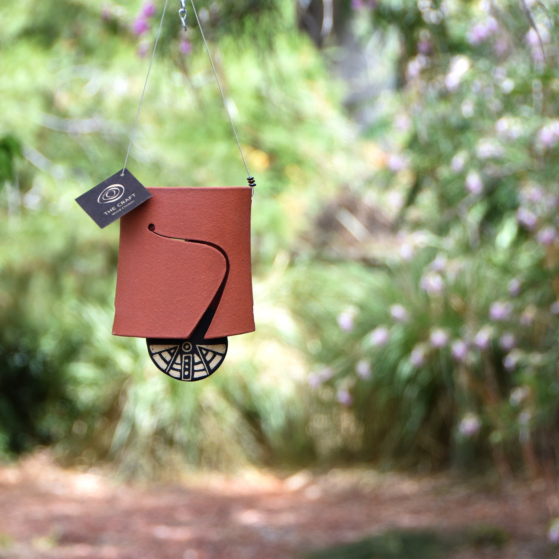 Modern, rustic red colored wind chime bell that was stained with red iron oxide and featuring a black and white sgraffito wind clapper